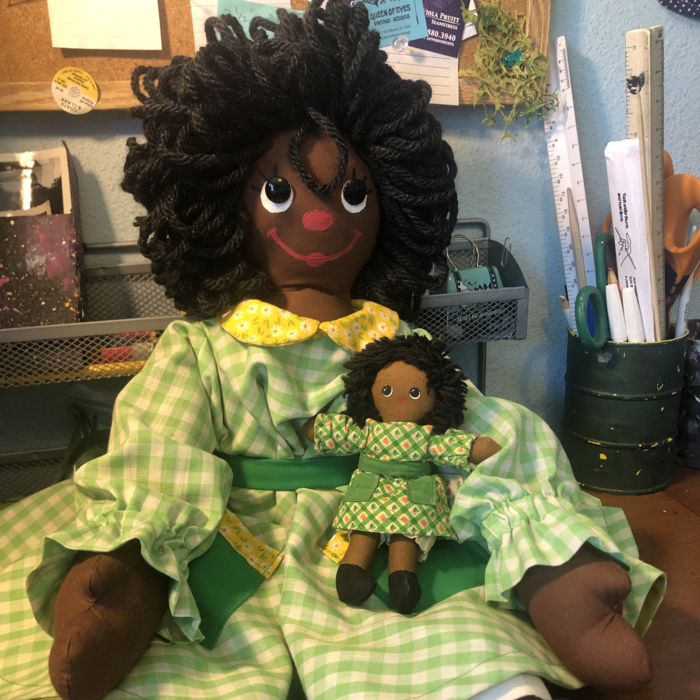A Black rag doll wearing a green sundress. Link takes you to project page.