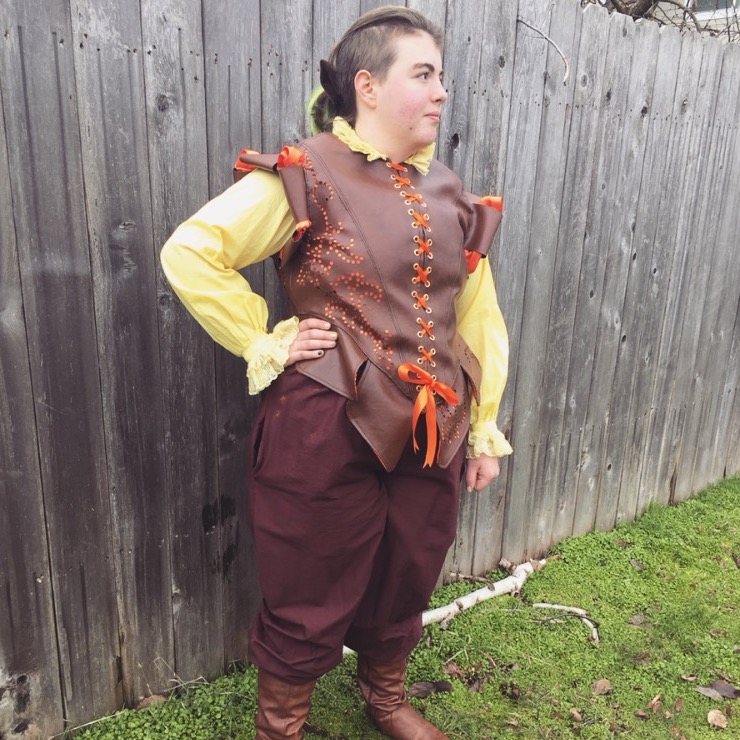 A full body image of a person dressed in Medieval costume, with a yellow undershirt and leather doublet. Link takes you to project page.