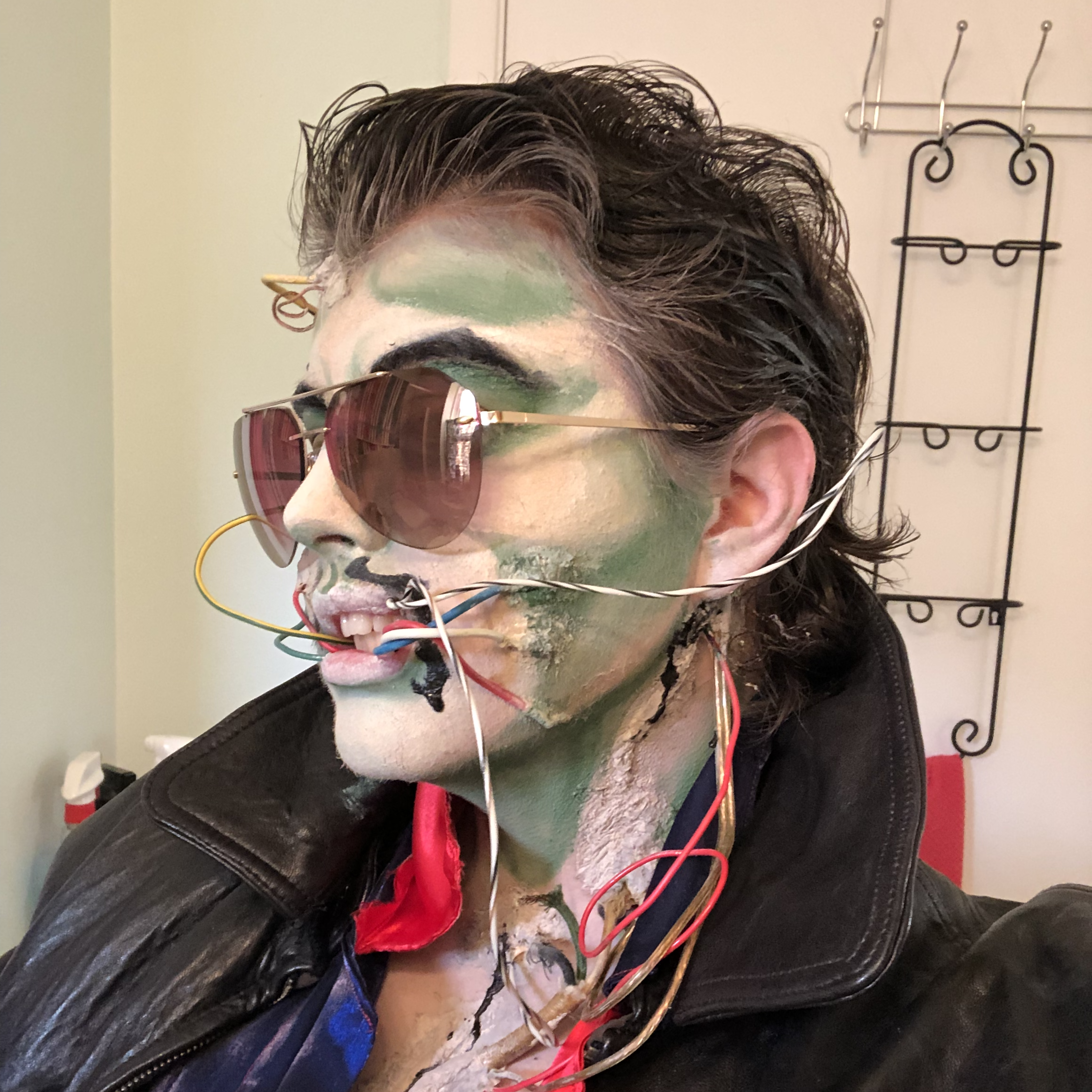 A headshot of a person with wires coming out of their skin and mouth, wearing sunglasses and a leather jacket. Link takes you to project page.
