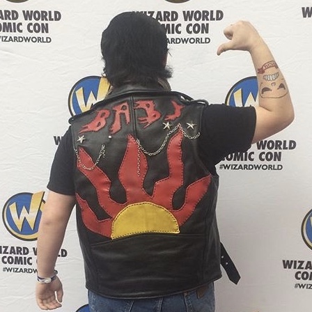A person standing with their back to the camera, showing off the back of a leather vest with a sun design. Link takes you to project page.