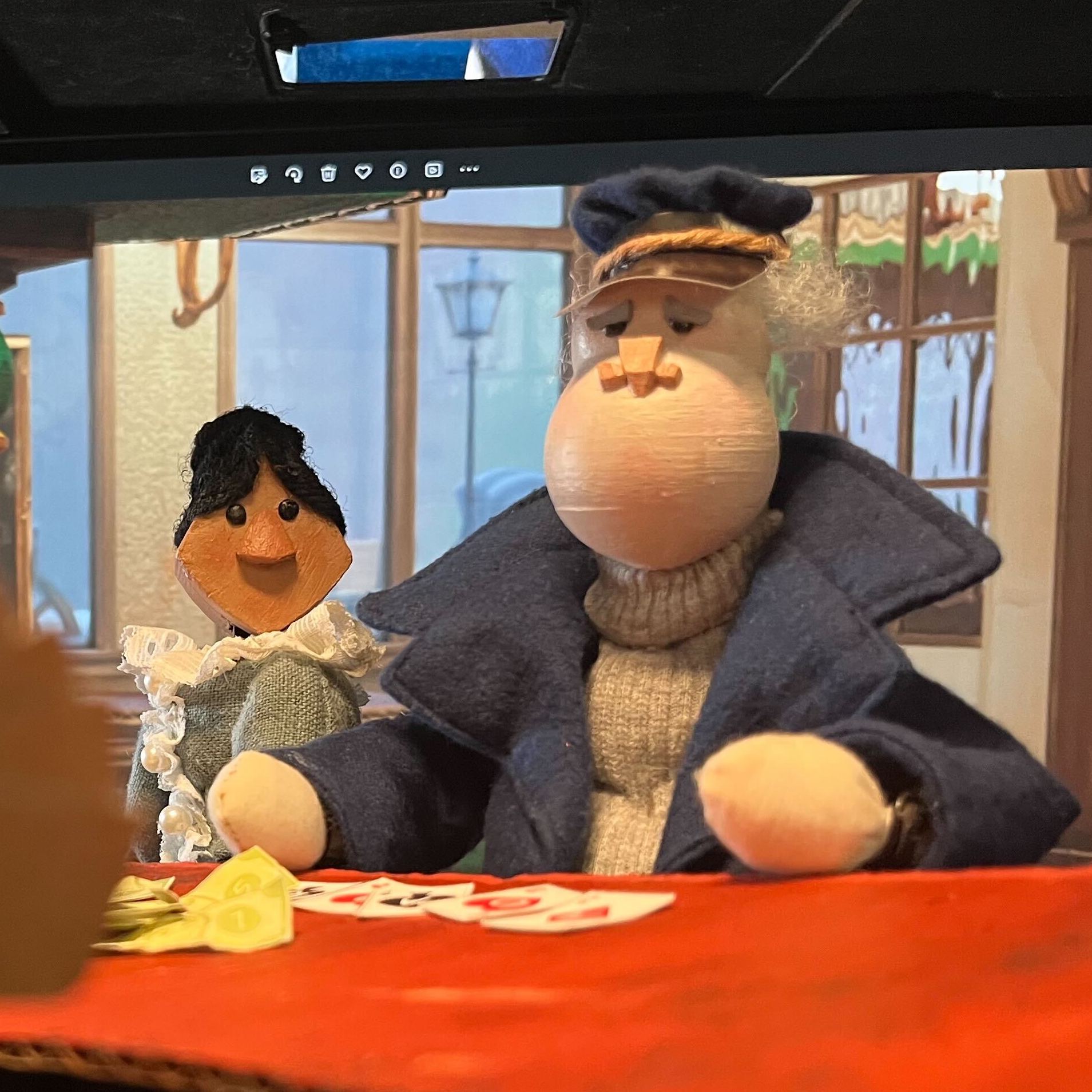 Two humanoid puppets sit at a table. The nearer one is dressed as a ship captain with wool sweater and a dark blue coat. The one in back wears a Victorian dress with lace. Link takes you to project page.