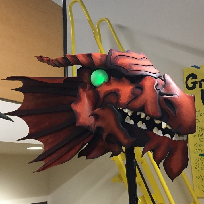 A large, red dragon head puppet with glowing green eyes and sharp teeth. Picture links to project page.